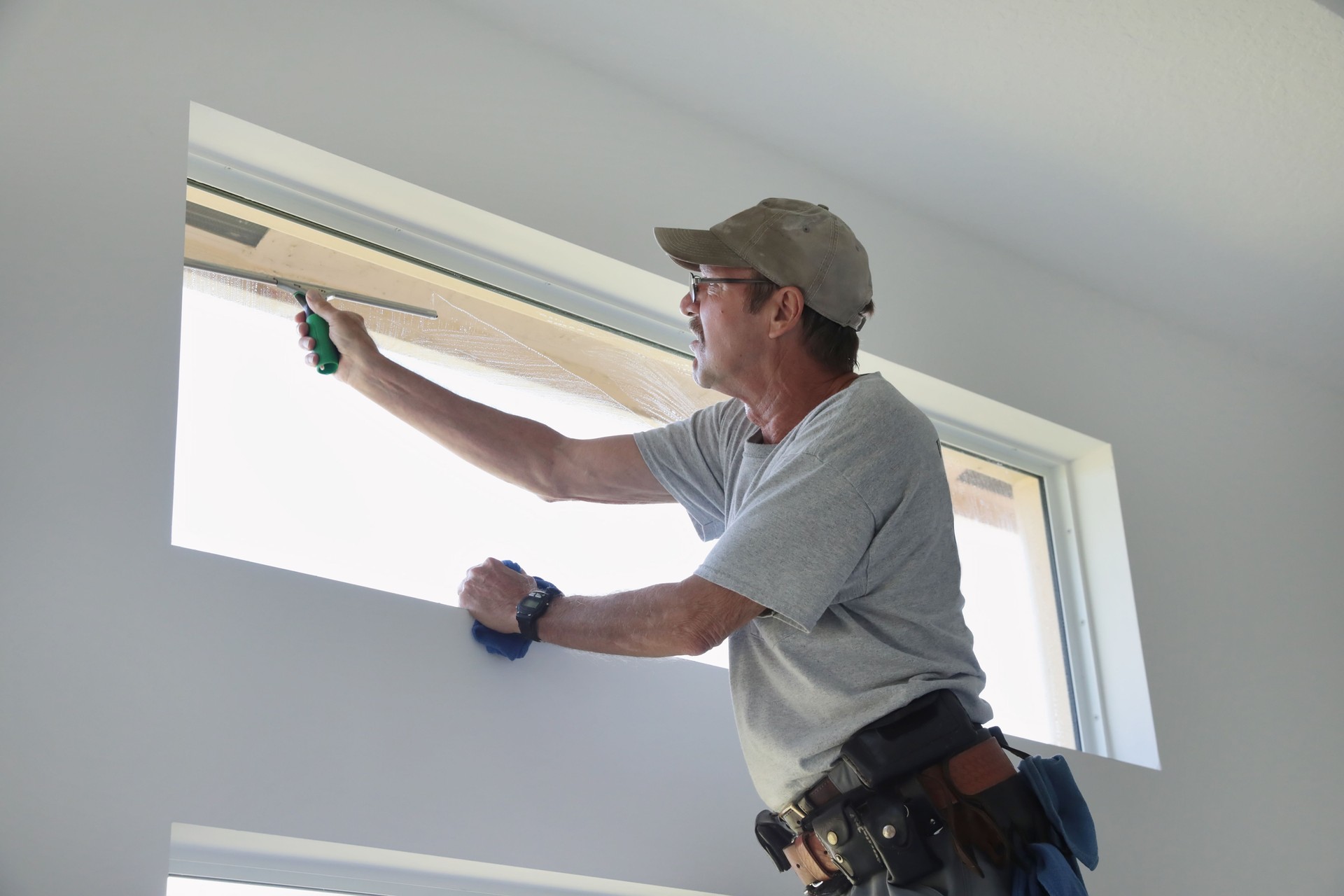 Series: Window washer cleaning inside transom window in a home